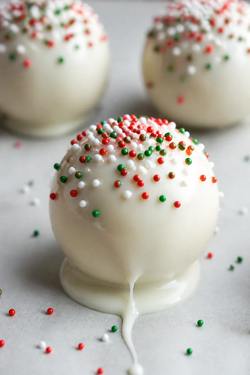 Close-up detail: A just-dipped Christmas Tree Cake truffle on parchment, glossy white candy shell wi