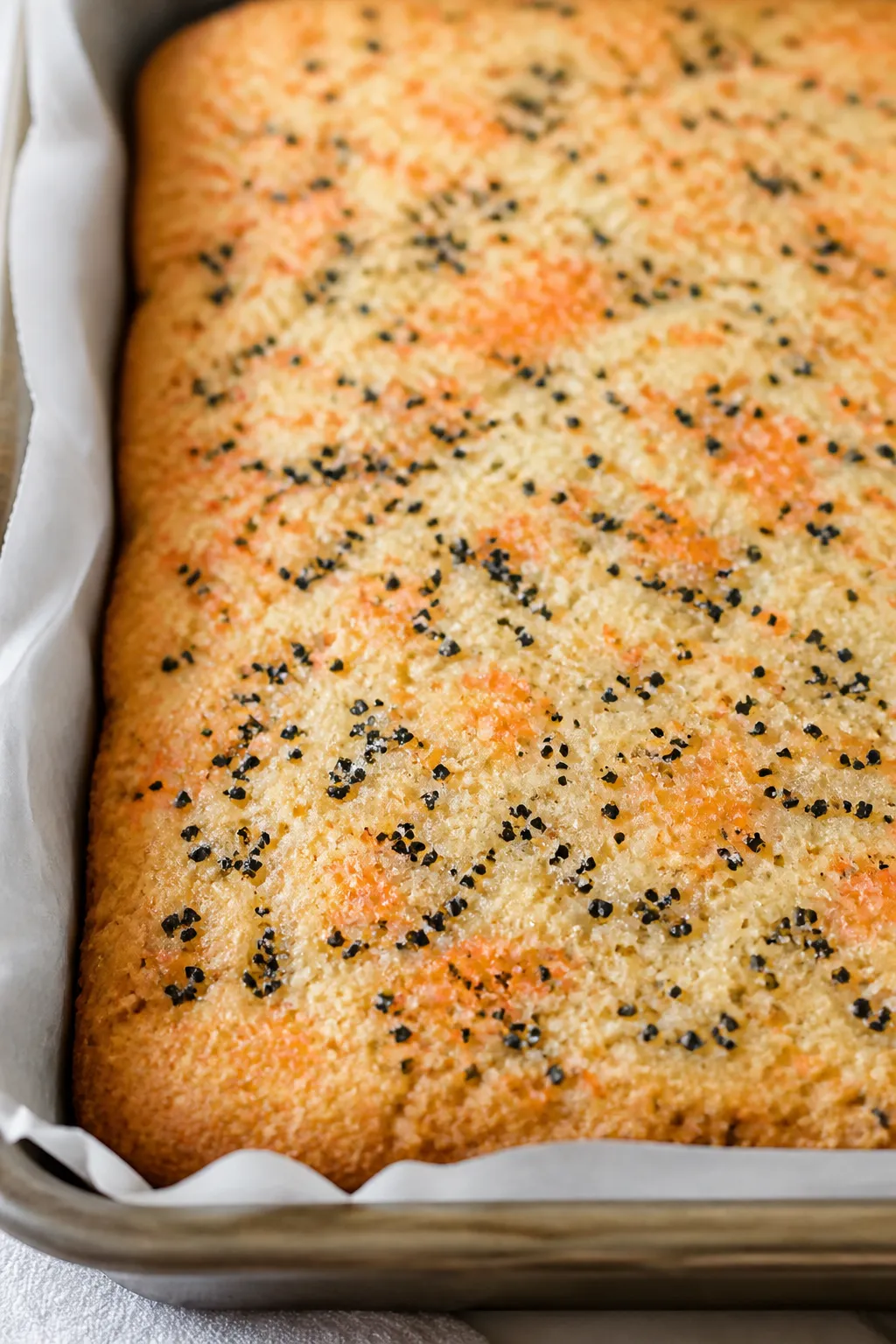 Close-up detail: A slab of freshly baked Halloween sugar cookie bars cooling on parchment in the 9x1