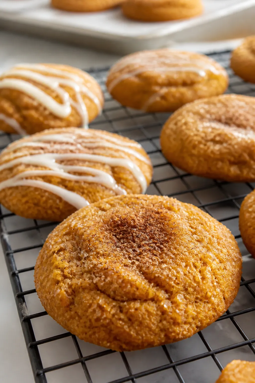 Close-up detail: Freshly baked pumpkin pie cookies cooling on a wire rack, edges set with slightly p