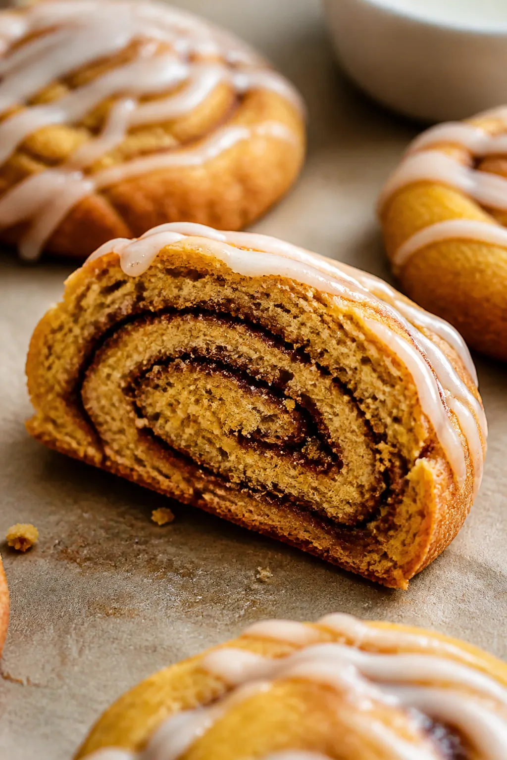 Close-up detail shot: A just-baked Pumpkin Cinnamon Roll Cookie sliced crosswise to showcase tight c