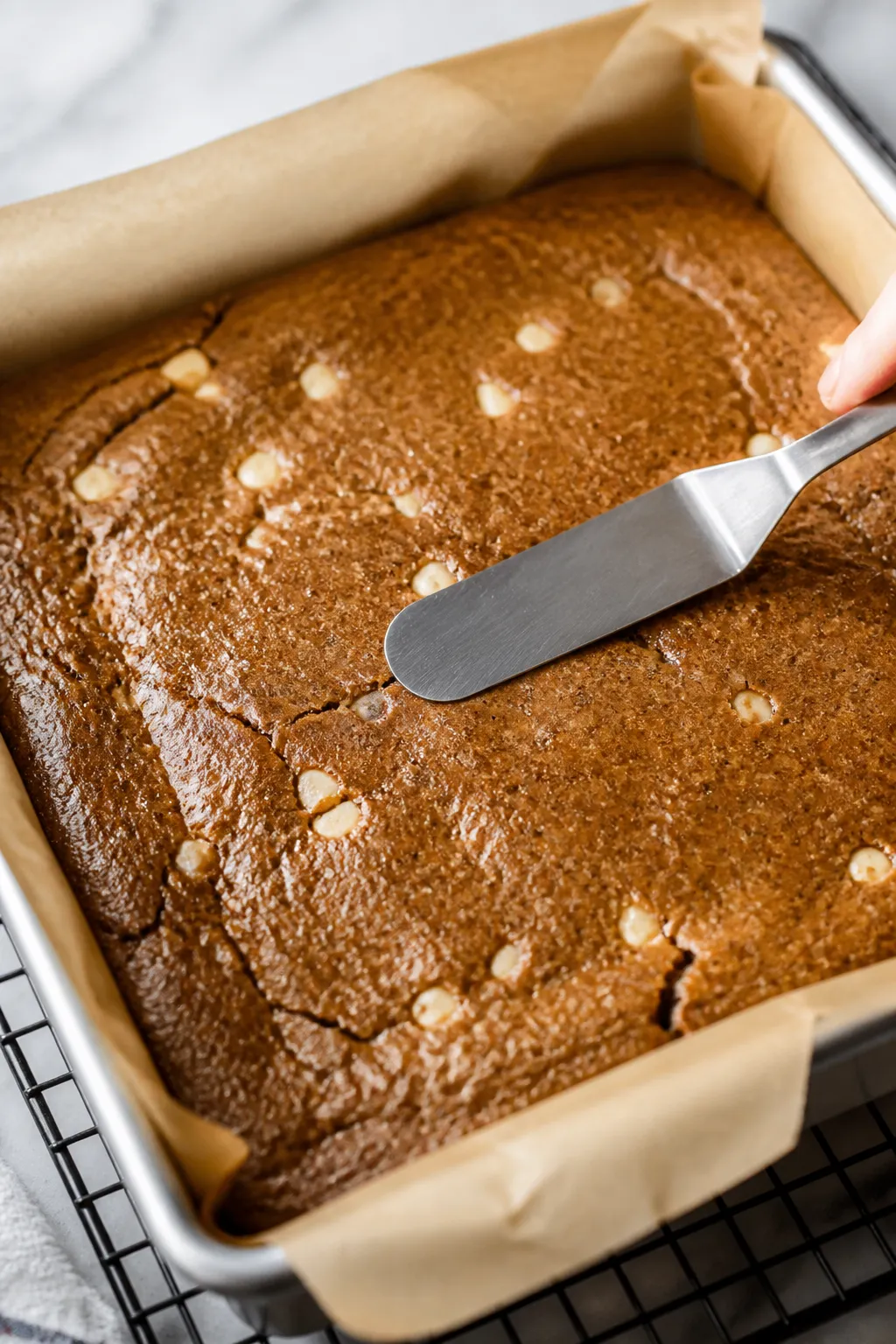 Close-up detail shot: A just-baked slab of gingerbread cookie bars still in an 8-inch parchment-line