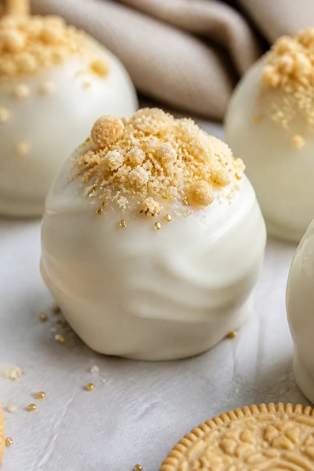 Close-up detail shot of a freshly dipped Golden Oreo truffle with a glossy white chocolate shell, fa