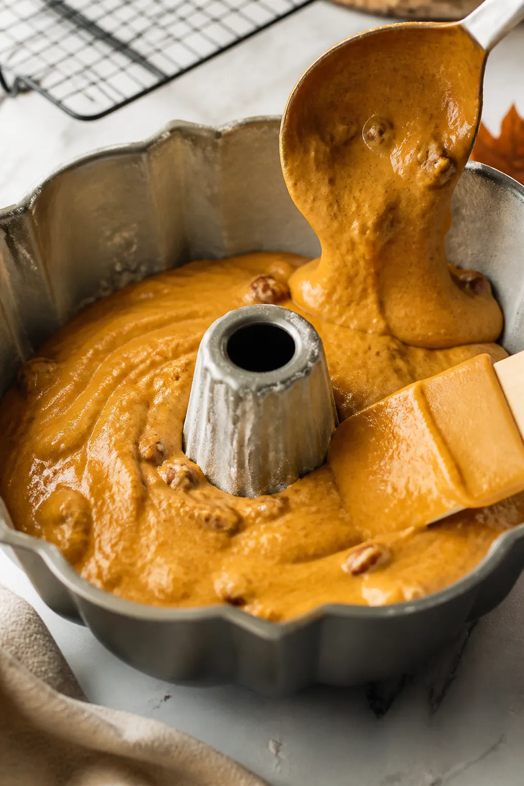 Cooking process — Close-up of glossy pumpkin spice batter being spooned into a heavily greased and