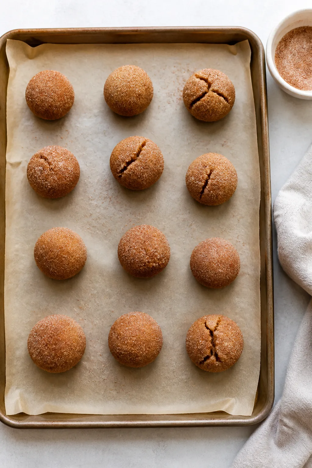 Cooking process: Overhead shot of cinnamon-sugar–coated dough balls arranged 2 inches apart on a p