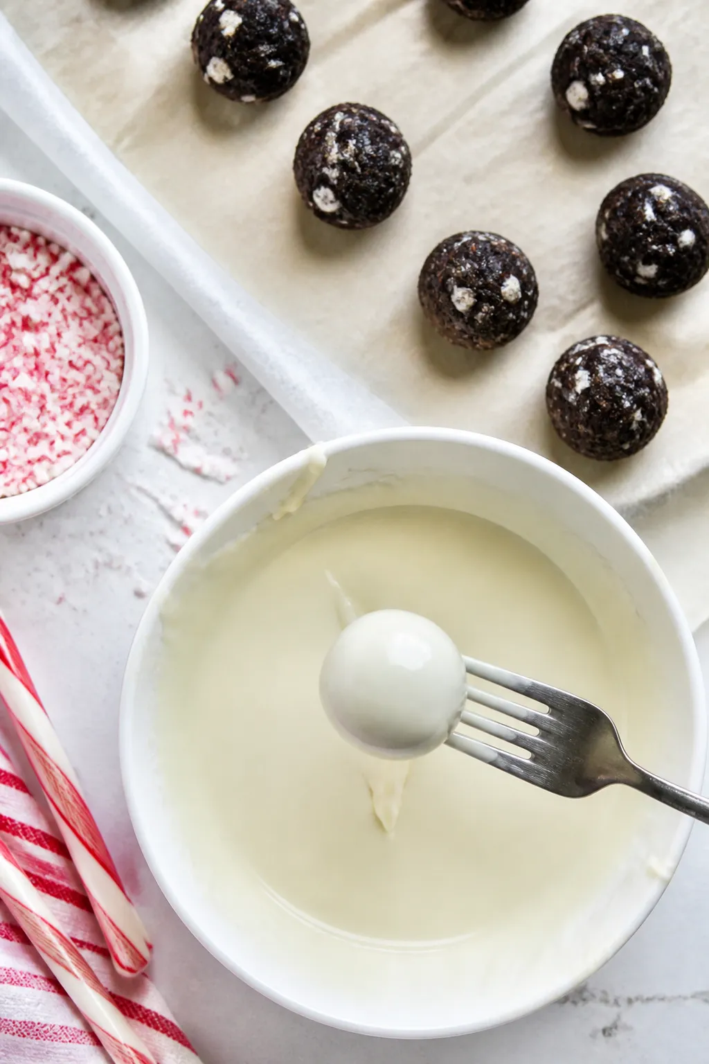 Cooking process: Overhead shot of firm, rolled truffle centers being coated—several 1-inch chilled