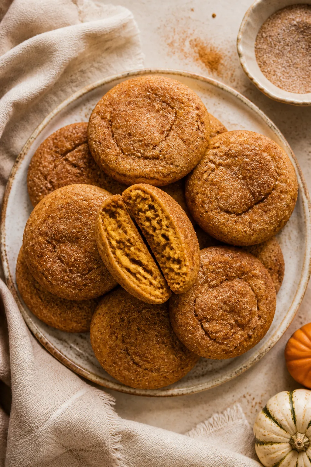 Final dish, overhead: A rustic ceramic plate stacked with soft, chewy pumpkin snickerdoodles, visibl