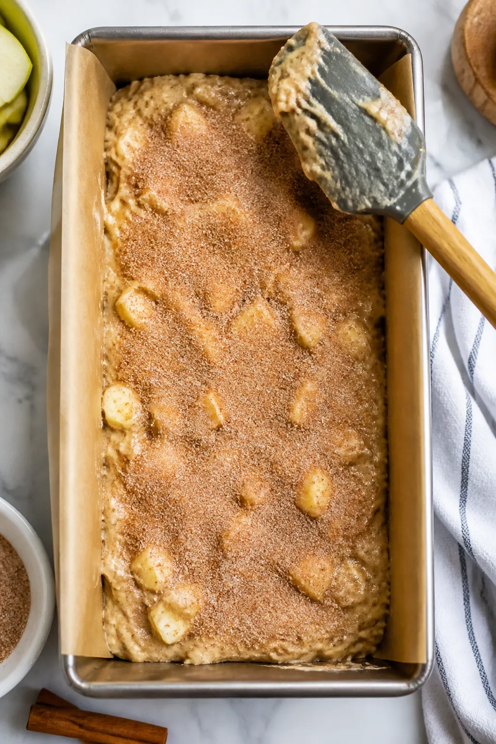 Process-in-pan shot of the batter layering step: a 9x5-inch parchment-lined loaf pan with half the t