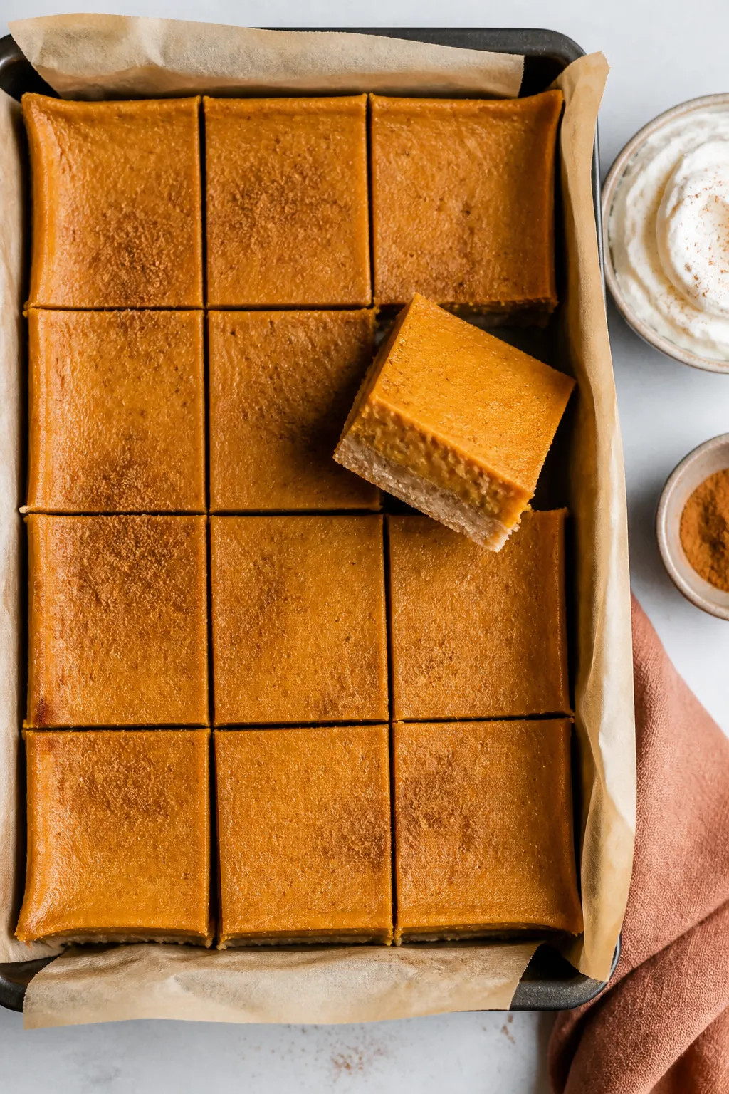 Tasty top view: Overhead shot of a 9x13 pan of fully set Pumpkin Pie Bars being sliced into neat squ