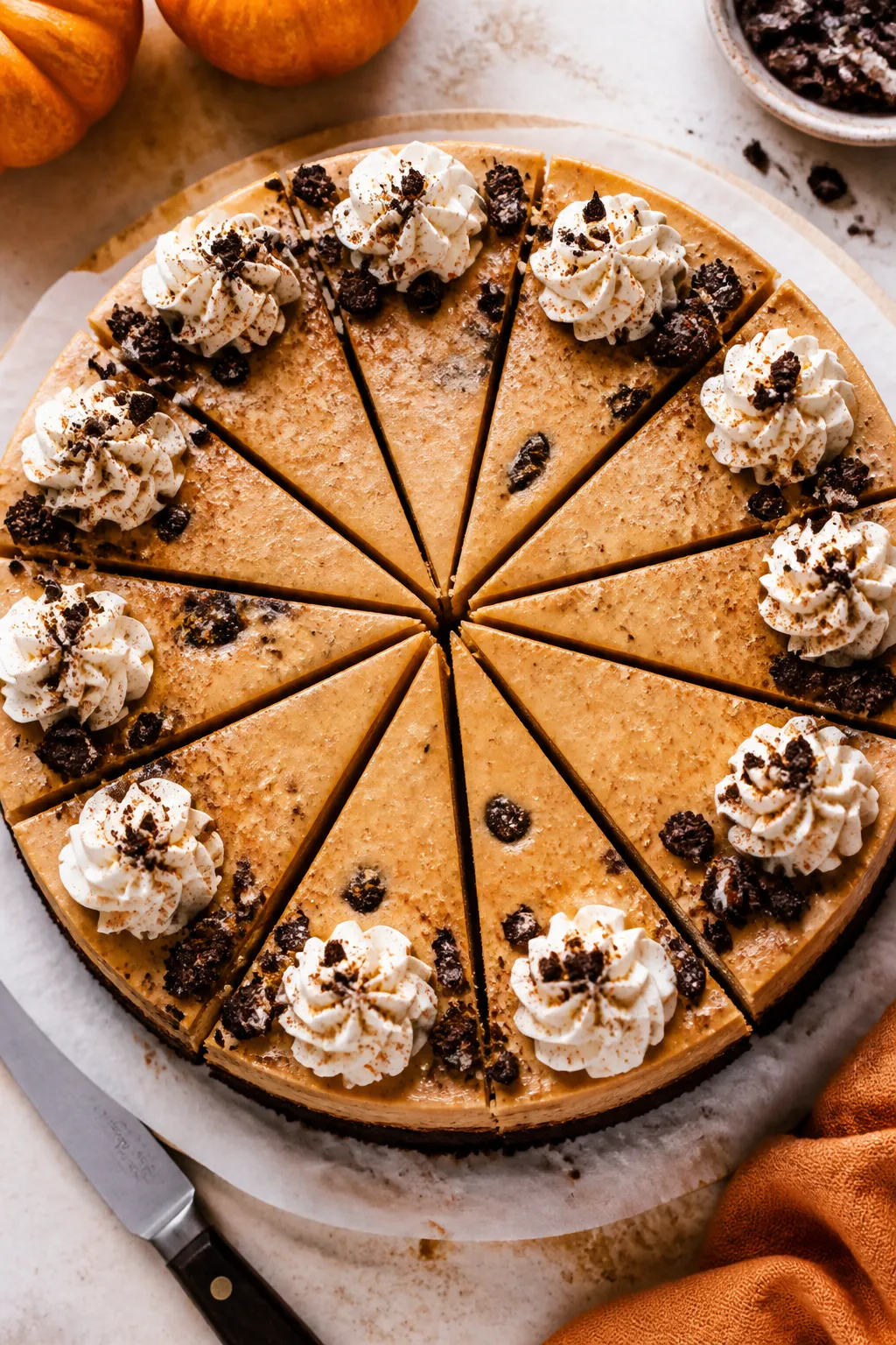 Tasty top view: Overhead shot of a fully chilled Pumpkin Oreo Cheesecake on parchment-lined cake boa