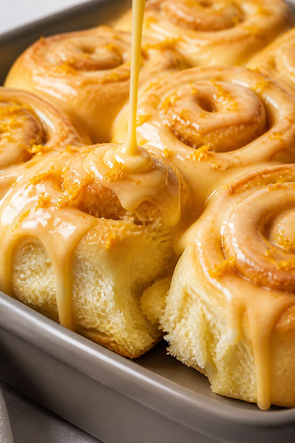 Close-up detail: A pan of freshly baked orange sweet rolls just out of the oven, lightly golden spir