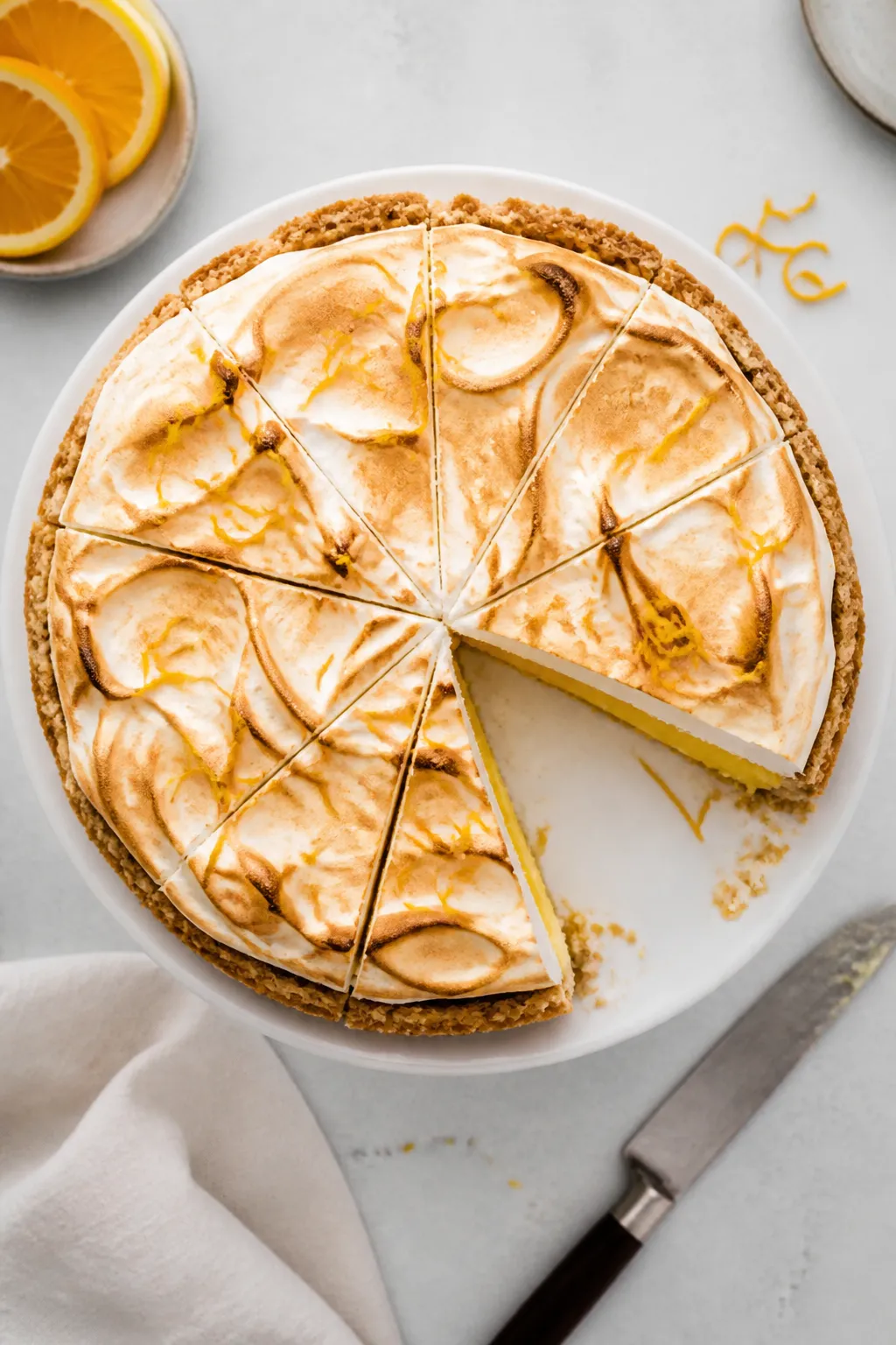 Tasty top view: Overhead shot of a chilled, neatly sliced Orange Meringue Pie on a white cake stand,