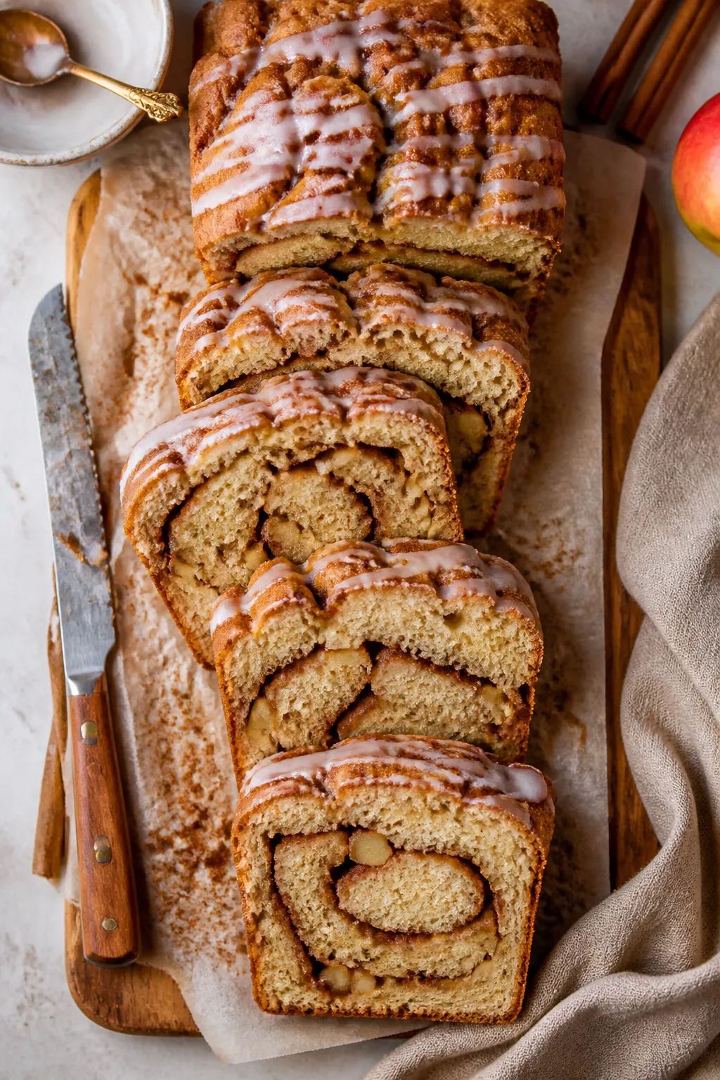 Tasty top view: Overhead shot of the Apple Fritter Bread sliced on a parchment-lined wooden board, r